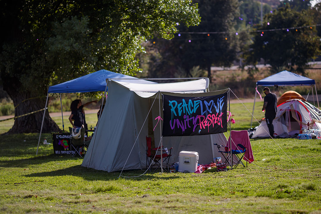 A tent with a "Peace Love Unity Respect" flag