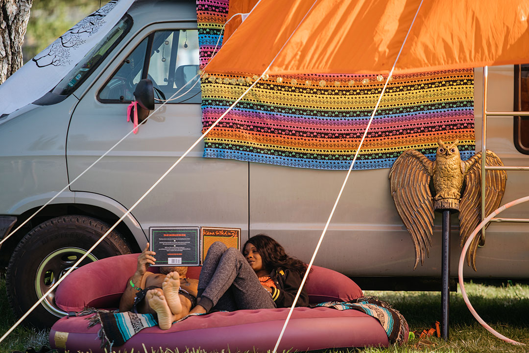 Campers relax under a shade structure