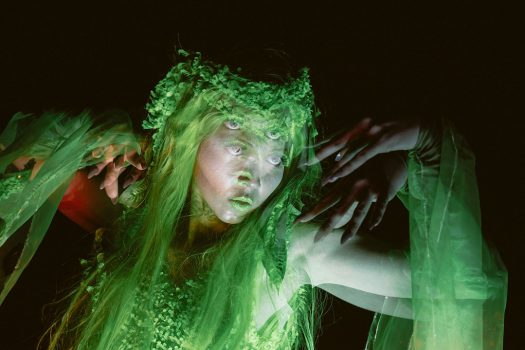 A double-exposed image of a performer in green