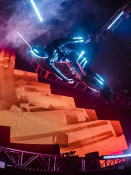 A futuristic performer flips through the air