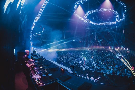 A DJ performs under blue light