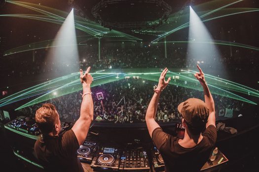 Two DJs with their hands in the air