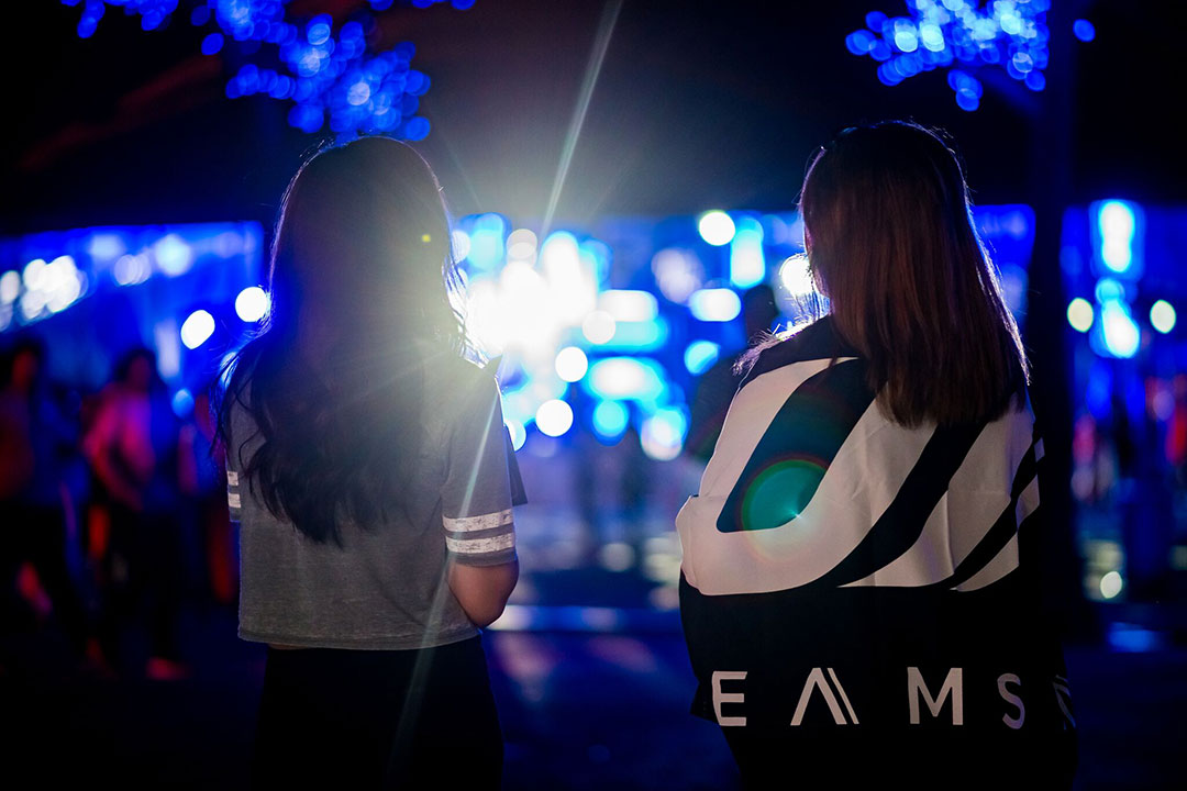 A girl wrapped in a Dreamstate flag stands with her friend