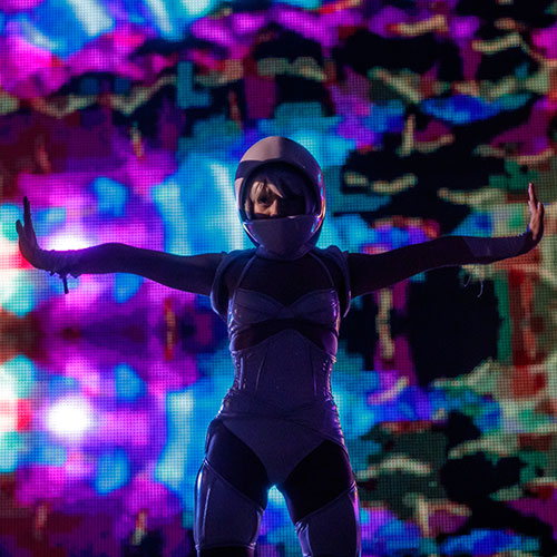 A helmeted performer with her arms out