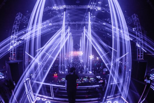 A DJ performs under purple lights