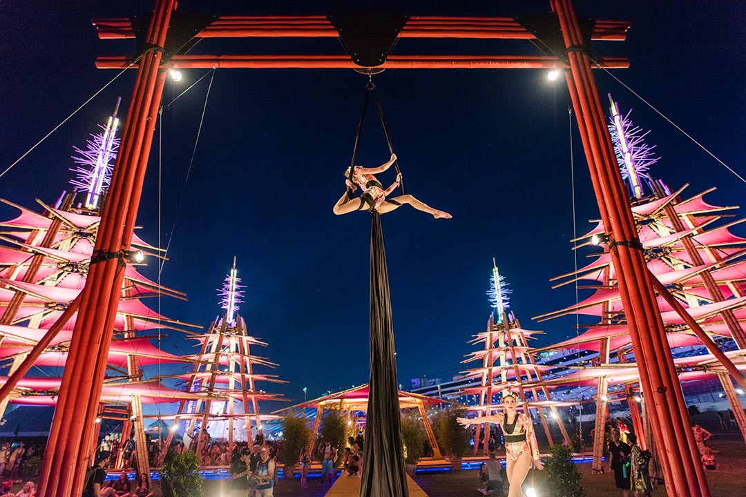 An aerialist at the bamboo temple performs high above a crowd gathered near cosmicMEADOW.