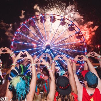 Headliners make heart hands at a Ferris wheel with fireworks
