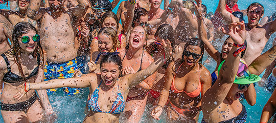 People in swimsuits laughing and splashing in a pool