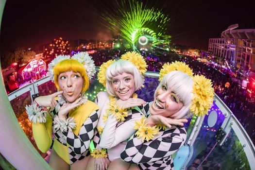 Three daisy-clad performers on a carnival ride