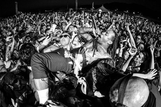 An artist crowd-surfs with a microphone